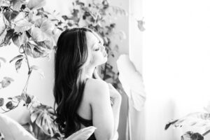 Woman exhales with her hand on her neck as she poses in a boudoir shoot with OC Boudoir in Orange County, California.