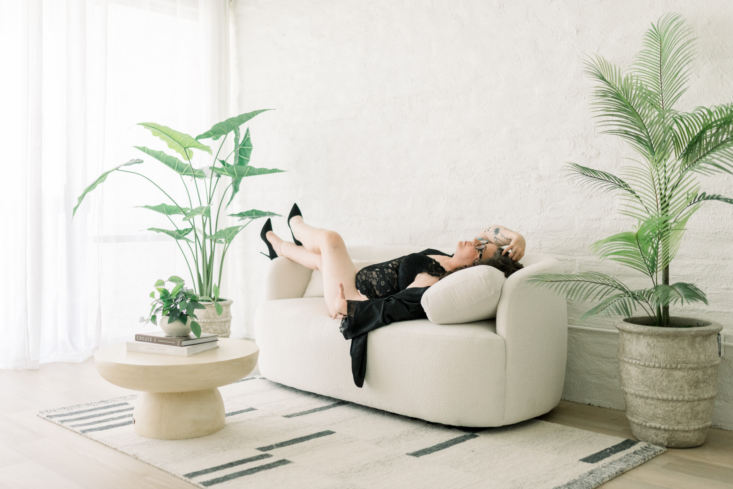 Boudoir photography for women over 40 featuring a confident woman relaxing on a sofa during an elegant portrait session.