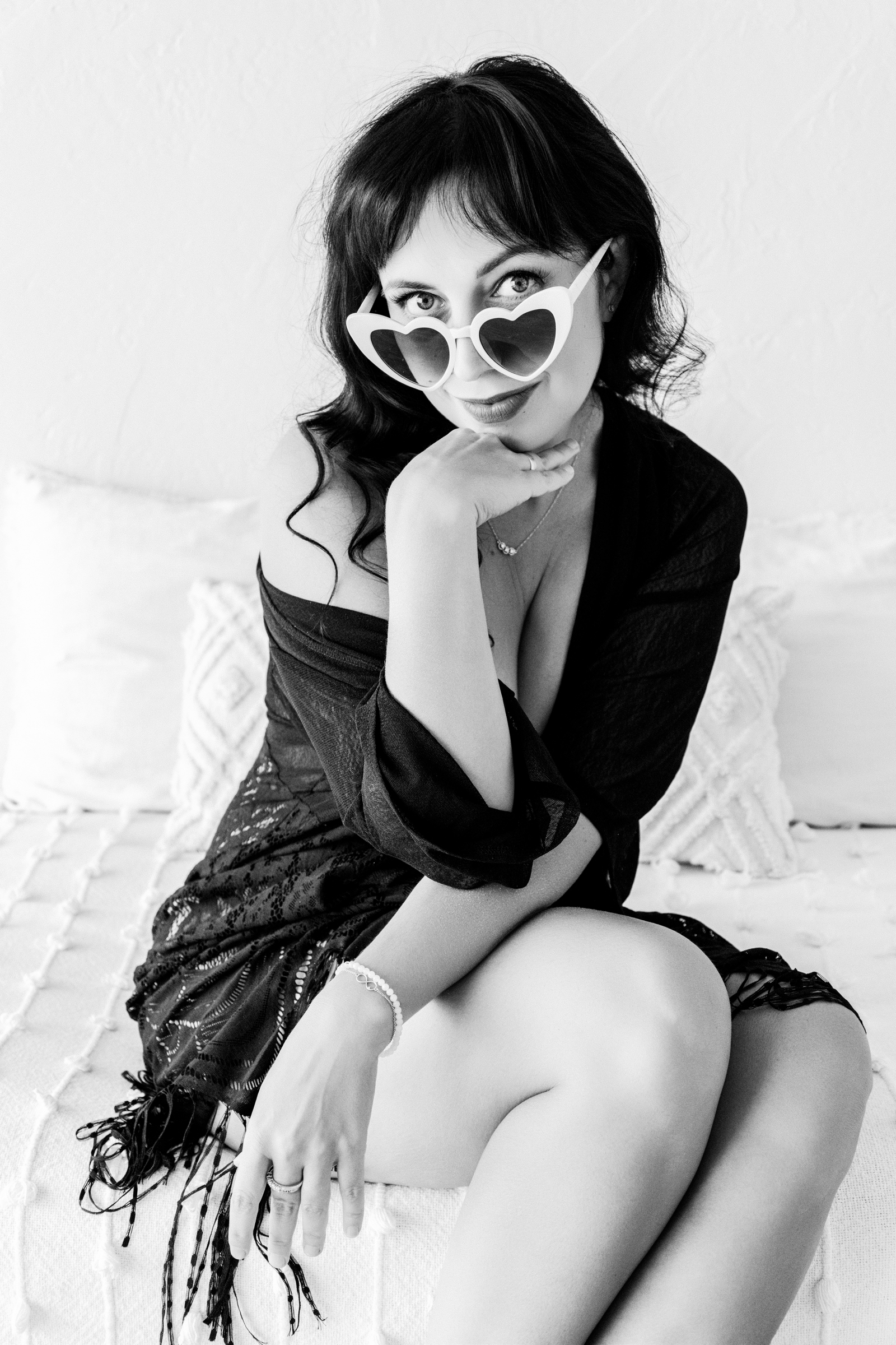 boudoir photoshoot ideas High-contrast monochrome boudoir portrait of a woman embracing her silhouette in a refined and empowering studio setting.