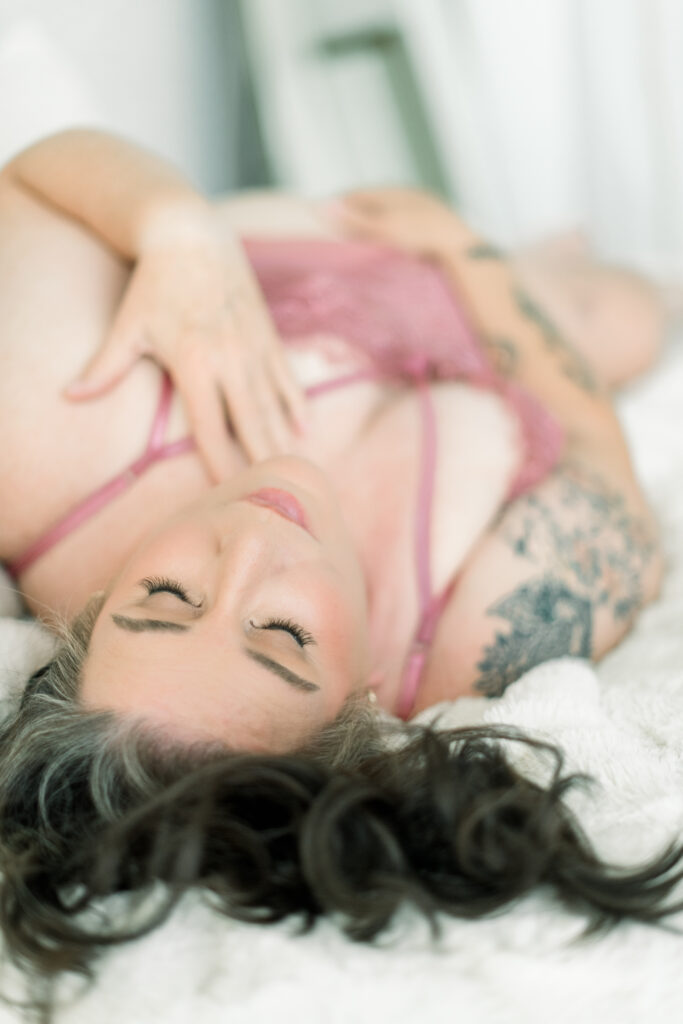 Why women book boudoir sessions again: a confident woman in pink lingerie posing gracefully during a luxury boudoir photography session.